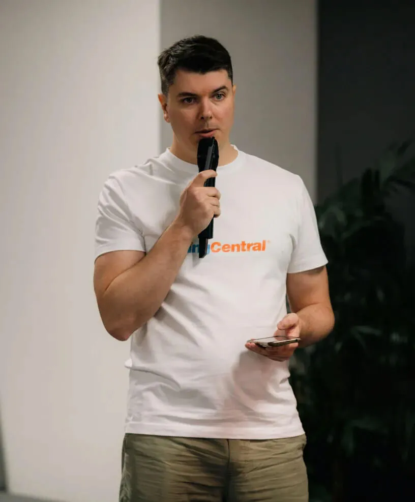 Мъж с тениска на RingCentral говори пред публика с микрофон