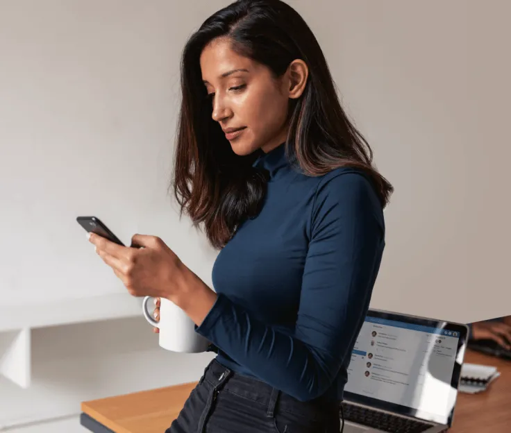 A woman using her phone while having a cup of coffee