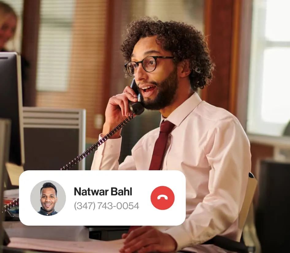 A man talking to a colleague via a deskphone connected to the cloud via the RingCentral Cloud Connector