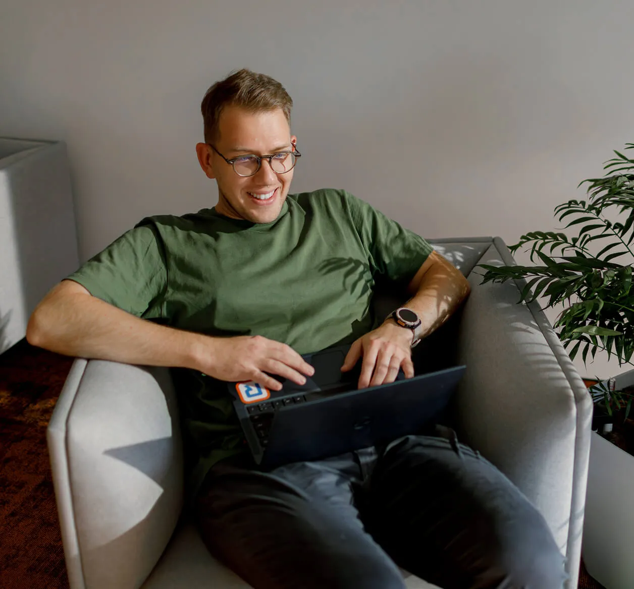 Усмихнат служител на RingCentral, работещ с лаптоп на диван