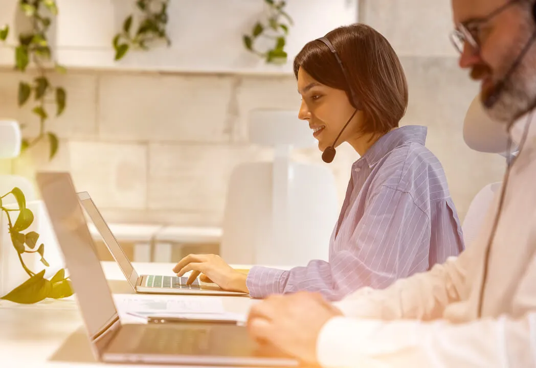 Two support agents wearing headsets speaking to customers