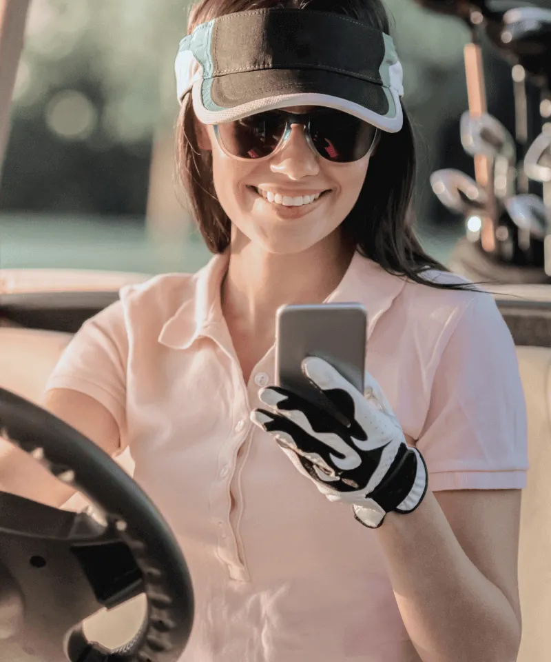 Eine TaylorMade-Mitarbeiterin, die am Golfplatz ihr Smartphone checkt