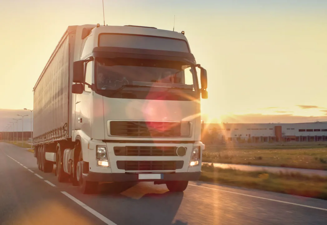 A semi-truck travels down a road in sunset light